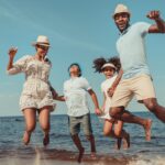 family jumping in the sand at the beach