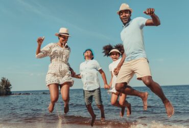 family jumping in the sand at the beach