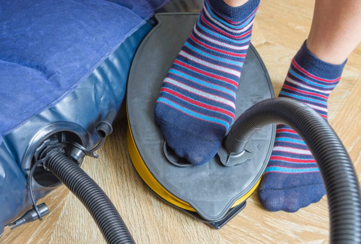 A woman with air foot pump pumps an inflatable mattress. (Photo: Yevhen Prozhyrko/Shutterstock)