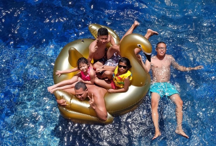 family floating in swimming pool relaxing