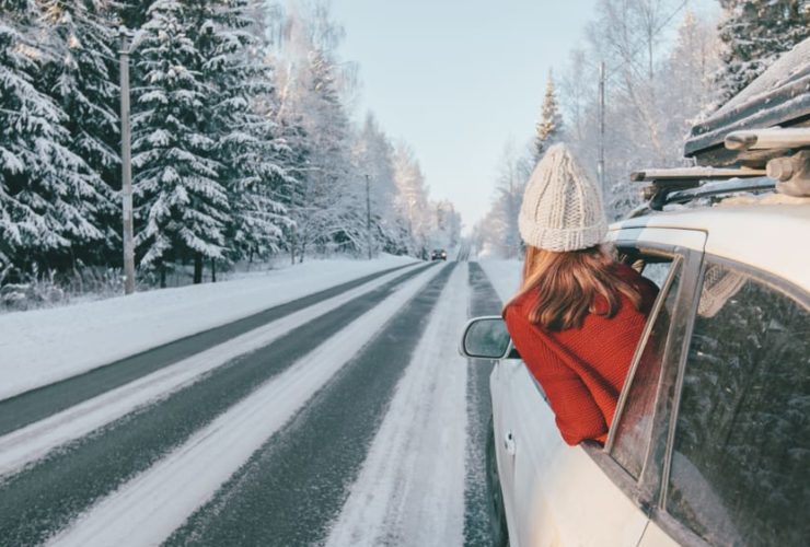 Teen girl in car over snowy forest on winter road trip.