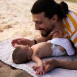 parent playing with baby at the beach: best baby sunscreens