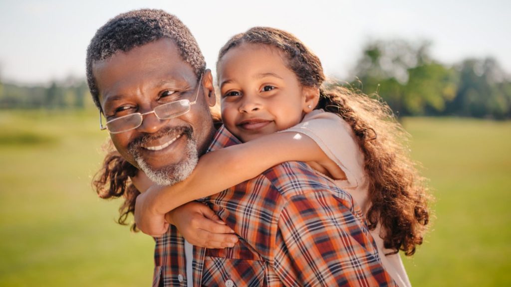 Happy grandfather giving a piggyback ride to his grandchild