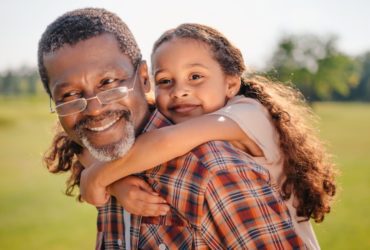 Happy grandfather giving a piggyback ride to his grandchild