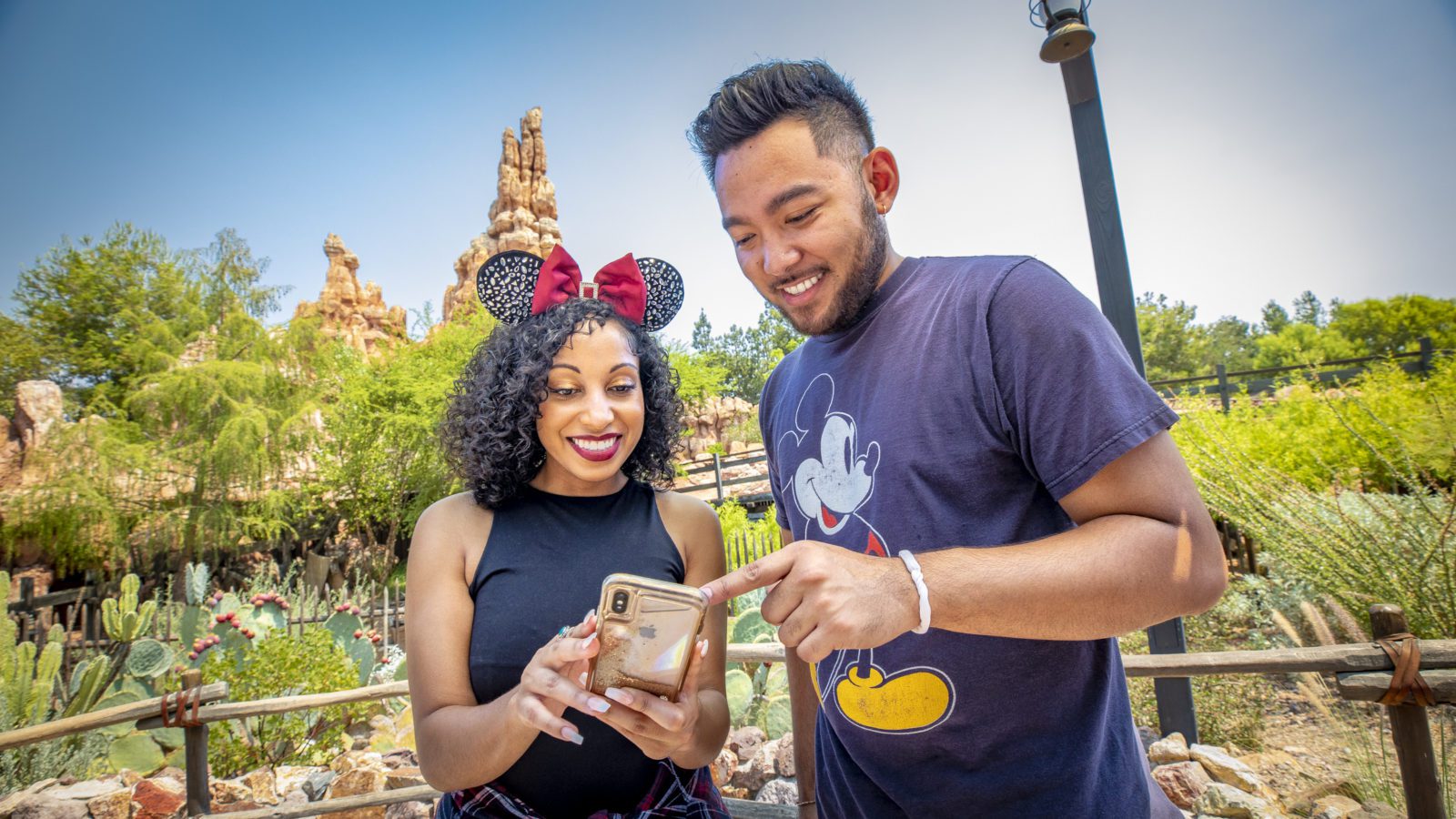 Two people at Disneyland looking at their phones