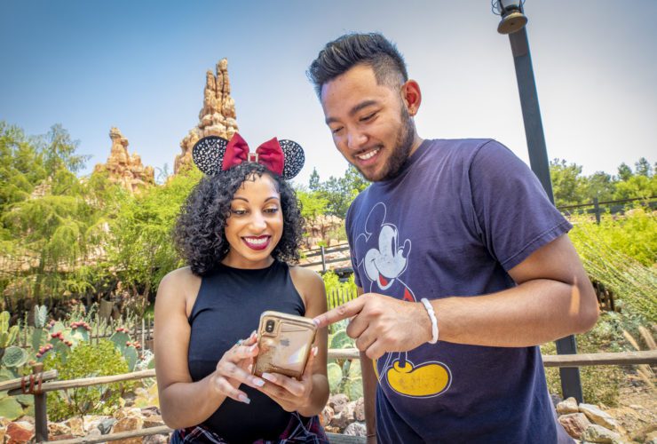 Two people at Disneyland looking at their phones