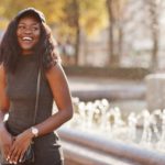 Woman standing next to fountain wearing a crossbody bag