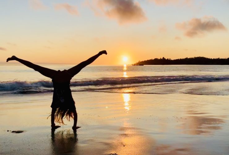 child doing a handstand at a Pacific Ocean Beach, a popular West Coast vacation stop for families