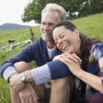 Laughing senior couple relaxing near mountain bikes in remote rural field (Photo: Trafalgar Tours)