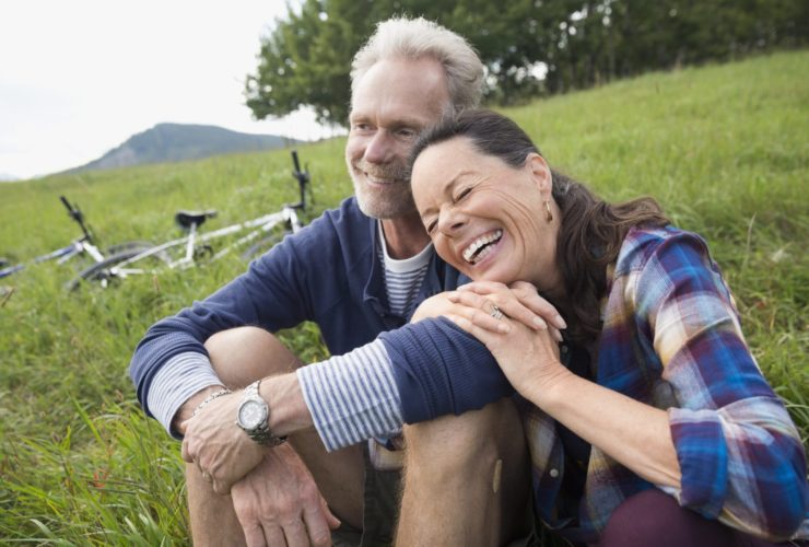 Laughing senior couple relaxing near mountain bikes in remote rural field (Photo: Trafalgar Tours)