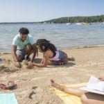 family on Midwest vacation building a sandcastle on the beach