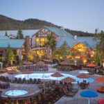 Exterior view of the Tenaya Lodge at Yosemite, with pools and trees in the foreground of the family friendly California resort