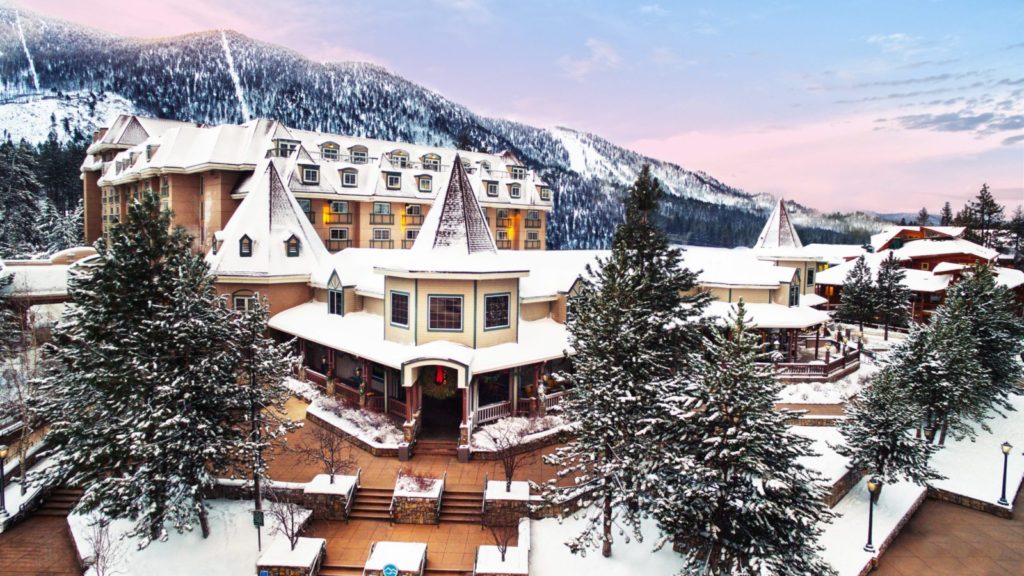 Lake Tahoe Resort Hotel exterior view with mountains of Lake Tahoe in background and snow