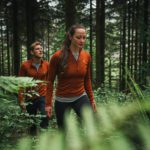 people walking through the forest wearing rust-colored Kora brand Yardang baselayers, which are warm and packable.