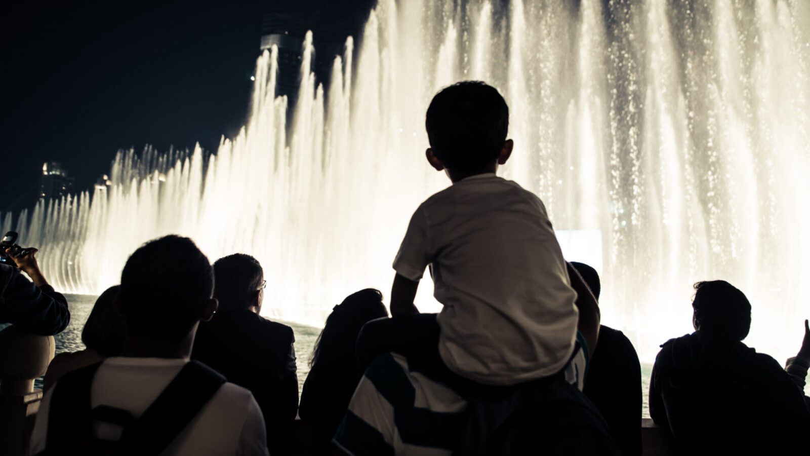 child on an adult's shoulders watching the evening fountain show at the Bellagio in Las Vegas