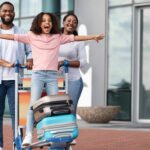 Happy kid standing on luggage cart as family leaves airport on a stopover