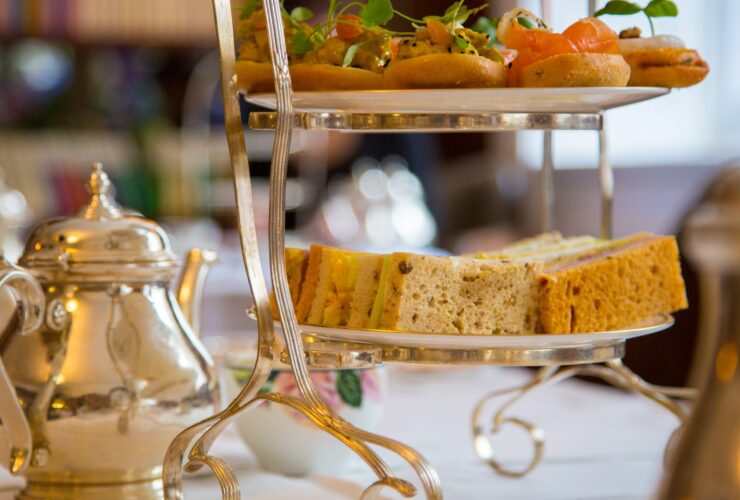 Afternoon tea setup with tiered sandwich tower and silver teapot