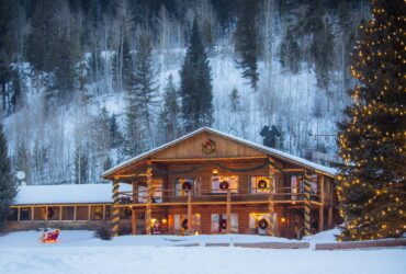 A cabin and tree decorated for the holidays in the snow