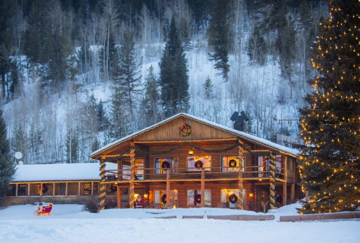 A cabin and tree decorated for the holidays in the snow