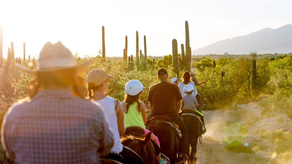 Children riding horeseback through desert