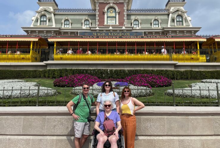 Dave Parfitt and his family, including kids and his wife, who uses a wheelchair, posing in front of Disney World Magic Kingdom train station