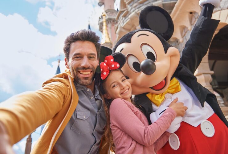 An adult and child taking a picture with Mickey Mouse at Disneyland Paris