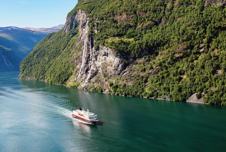 Cruise ship sailing through a mountainous village in Norway