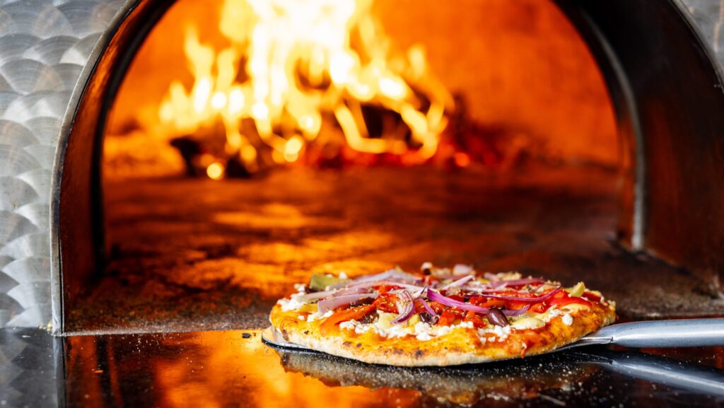 A pizza coming out of the wood-fired pizza oven at The Inn at Stonecliffe