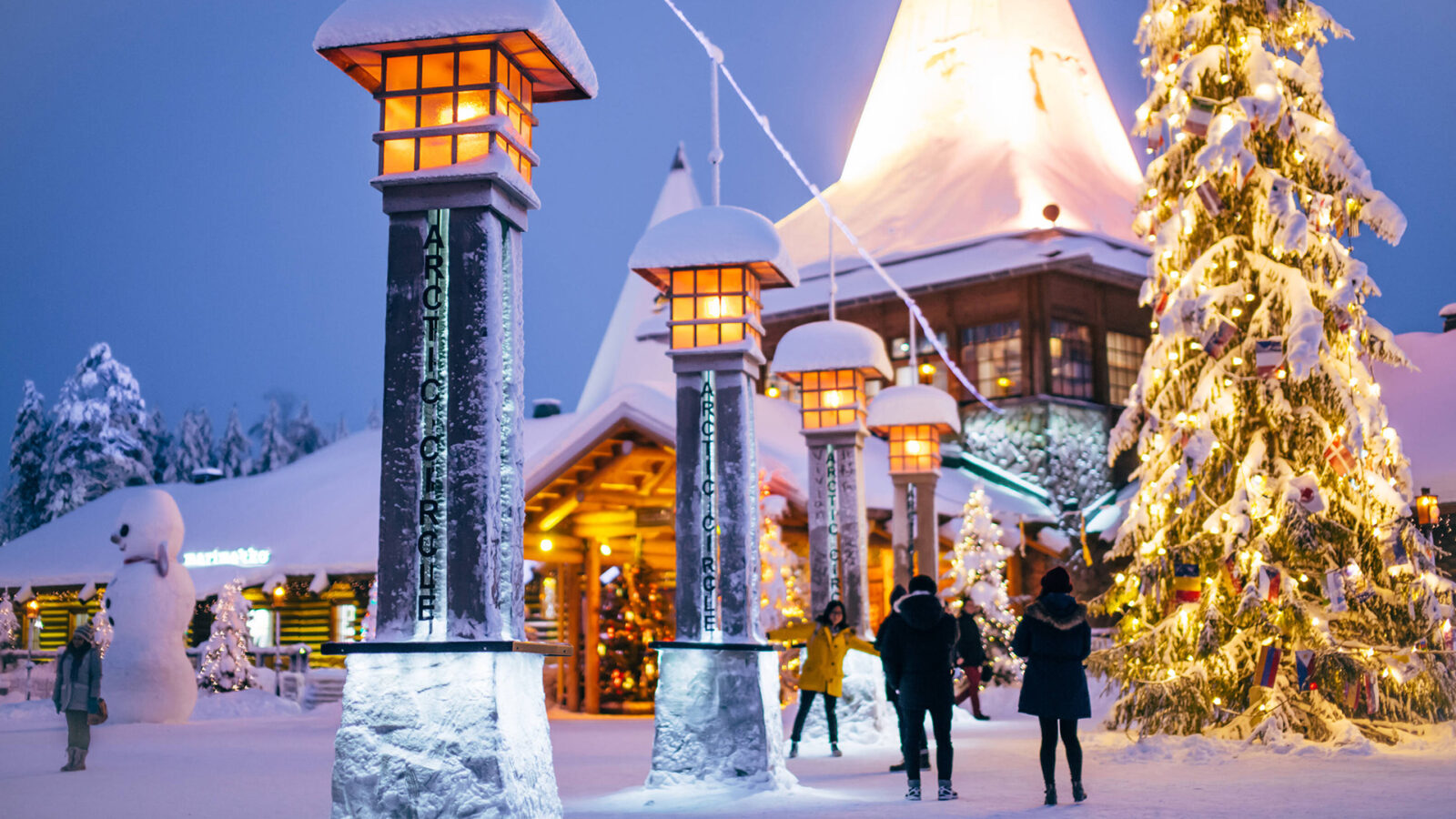 A snowy village surrounded by lanterns, a tall Christmas tree, and people walking around