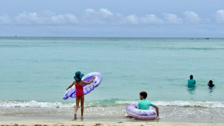 Kids playing in the calm waters at Waikiki Beach near the Royal Hawaiian